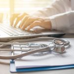 Stethoscope on prescription clipboard and Doctor working an Lapt